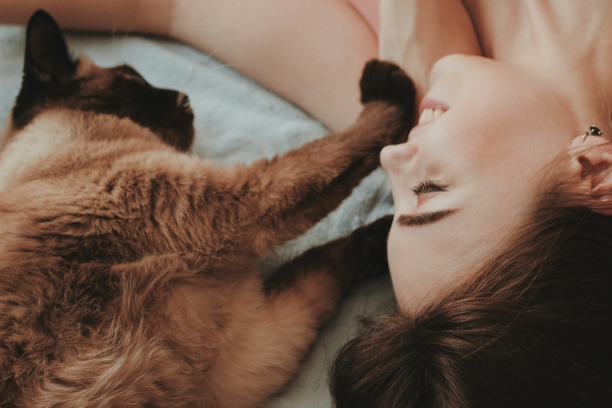 a woman and cat lying on a bed